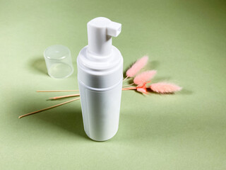 open white blank pump plastic bottle and natural dried pink spikelets on khaki paper background