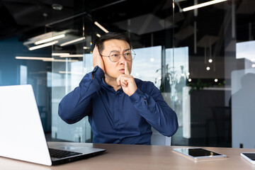 Upset and nervous asian man at workplace demanding silence from colleagues, businessman holding...
