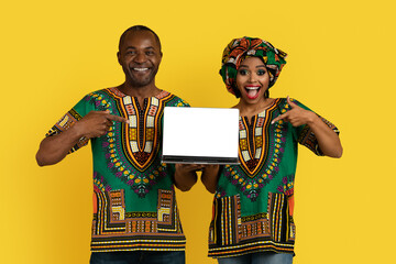 Bright black couple in african costumes holding laptop, mockup