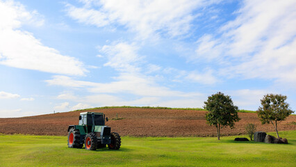 green tractor is parked in the middle of the farm.