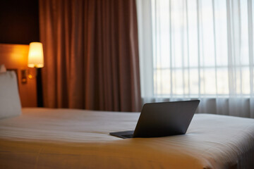 ホテルの客室のベッドと開いたノートパソコンの様子