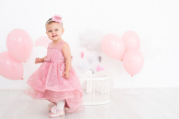 happy little girl in pink dress celebrating her first birthday with balloons