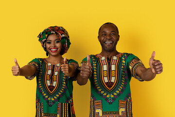 Obraz premium Cheery black man and woman in costumes showing thumb ups