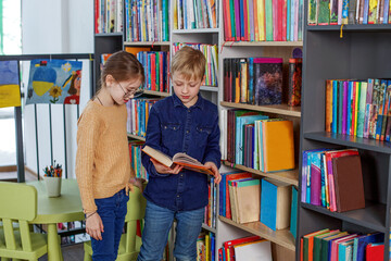 Cute little children reading books in library. Concept of studying, back to school and friends.