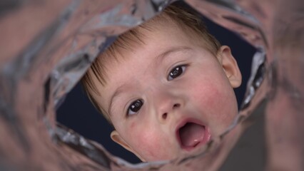 A little boy looks into a bag of chips. The child is interested in what the package is. First-person view from a bag of chips.