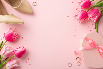 Women's Day concept. Top view photo of bunches of fresh flowers tulips heart shaped present box beige high-heel shoes gold rings and sprinkles on isolated pastel pink background with copyspace - obrazy, fototapety, plakaty