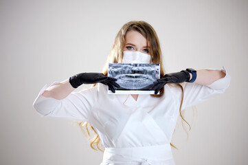 beautiful female dentist in mask holds panoramic shot of oral cavity in hands black gloves confidence doctor nurse assistant dental treatment prosthetics removal of teeth roots filling canals x-ray