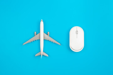 An airplane miniature and computer mouse on blue background, flat lay.