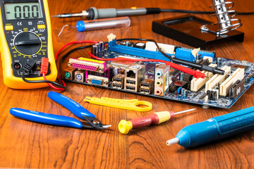 Repairing tools for malfunction computer mainboard on table. Fixing computer tools.