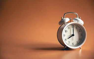 White alarm clock on brown background isolated.