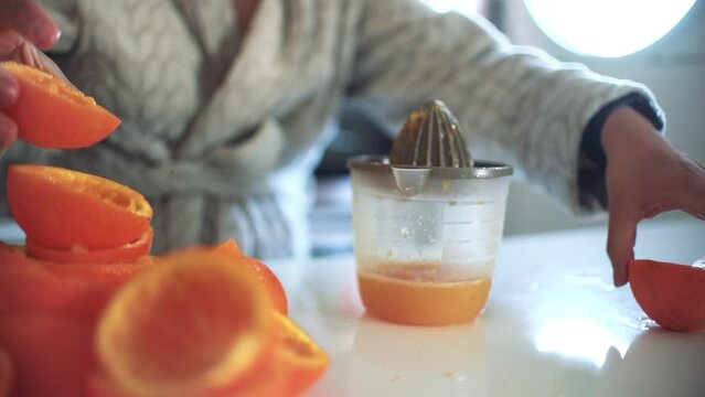 Woman using orange juicer, squeezer, reamer preparing an orange juice at home.