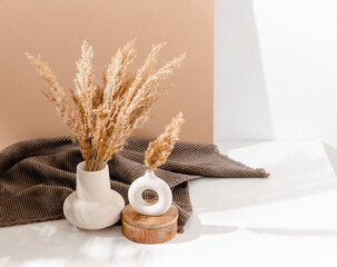 Ceramic vase set with pampas grass on the table with brown towel at the background and copy space,...