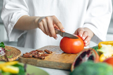 A woman cuts vegetables for a salad, close-up.