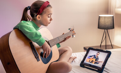 Little girl learns to play the guitar, online music video lesson.