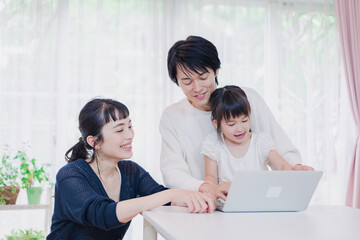 子供と一緒にパソコンで遊ぶ家族