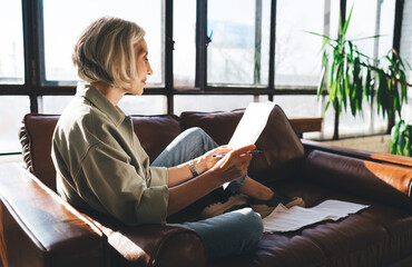 Focused woman reading papers on couch