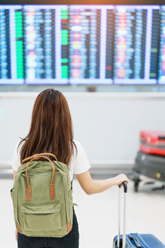Young woman with backpack looking at the flight time information board in international airport, before check in. Travel, Vacation, trip and Transport concept