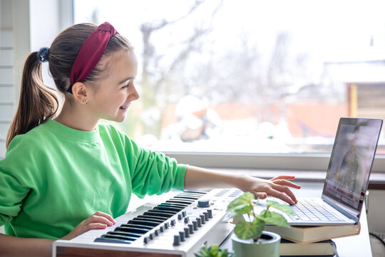 A girl learns to play the piano with a teacher online, remote learning music.