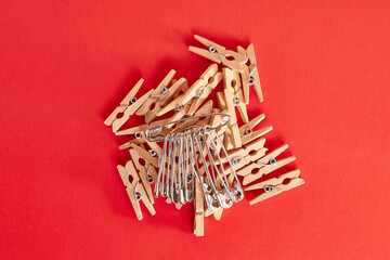 Pile of wooden clothespins and pins on a red background.