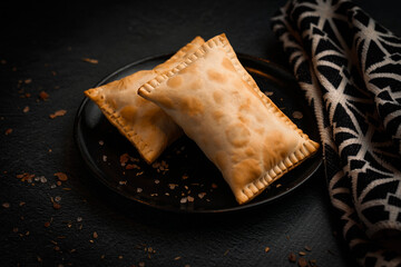 Empanadas argentinas tradicionales horneadas sobre fondo negro