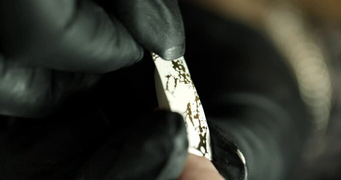 pasting a sticker with a pattern on a nail in a beauty salon. the master does a manicure. vertical video