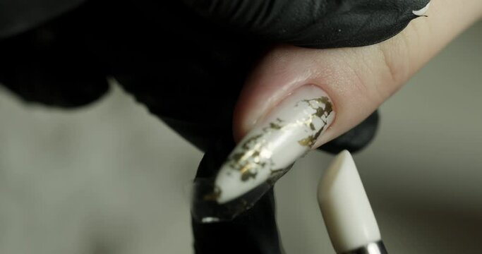 pasting a pattern on a nail in a beauty salon. the master does a manicure. vertical video