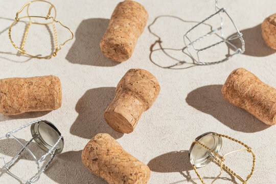 Creative composition made of champagne corks on beige sunlit background with shadow. Bottle caps from sparkling wine and metal wire muselet. Summer party drink concept
