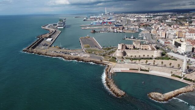 Panoramic view of the city of Civitavecchia with the adjoining tourist port and Forte Michelangelo. Emerald sea and view with tropical palm trees. Ferris wheel and cloudy sky.