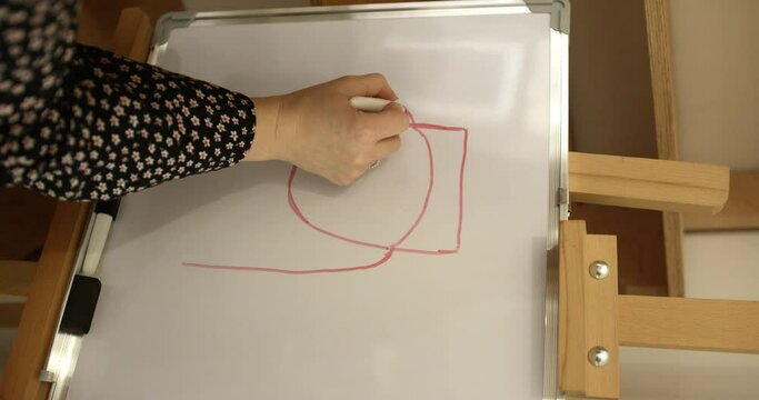 a woman's hand draws the structure and shape of a nail on a blackboard with a red felt-tip pen. the hand draws a nail