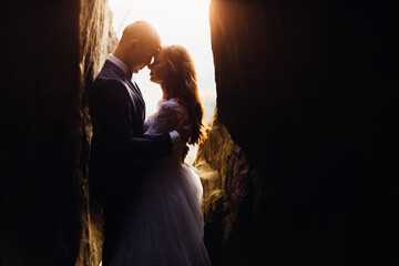 A romantic couple is hugging and standing among the rocks on the