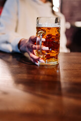 woman holds a glass of beer in his hand at the bar or pub