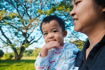 Mom hand lifting happy 1 year baby boy in tree park