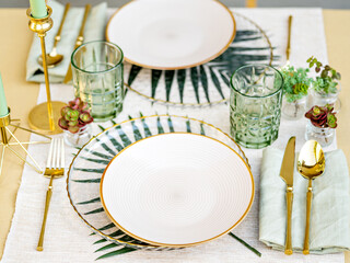 Sophisticated floral table setting. white crockery, golden cutlery and white table linen make a luxury setting. The formal elegant composition is perfect for a birthday banquet, a date or a wedding. 