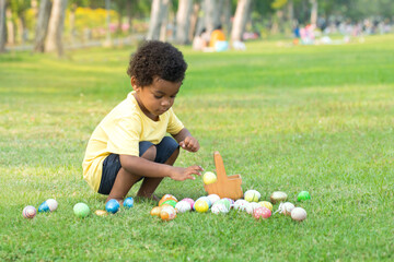 Little African boy pick up Easter egg in garden, Easter eggs hunting outdoors