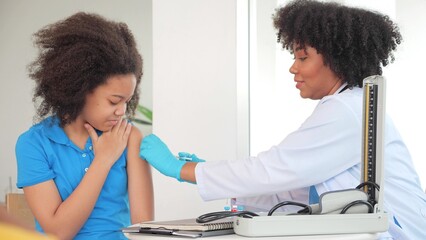 African-American children getting vaccine in clinic or hospital, with hand nurse injecting vaccine...