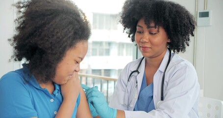 African-American children getting vaccine in clinic or hospital, with hand nurse injecting vaccine...