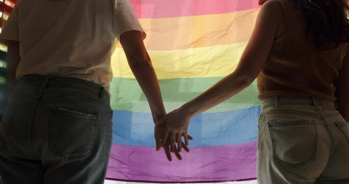 Girls hands approaching on an LGBT flag. Embrace and holding each other. LGBT Love, lesbian couple enjoying. LGBT rights, Lesbian family. Two women sharing love and support holding hands.
