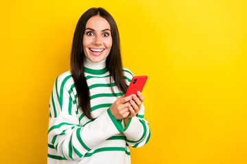 Photo of funny excited woman wear striped sweater typing modern device empty space isolated yellow color background