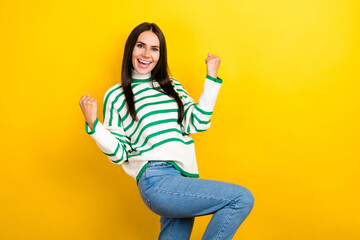 Photo of pretty lucky woman wear striped sweater rising fists screaming empty space isolated yellow color background