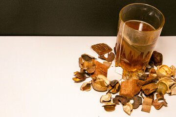Infusión caliente en un vaso de cristal con flores secas alrededor con una cucharilla de metal...