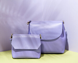 A fashionable female casual handbag. Springtime and summertime purse collection. Pastel purple clutch, modern elegant design. Colorful studio photo with purple background. Sale, merchandise concept.