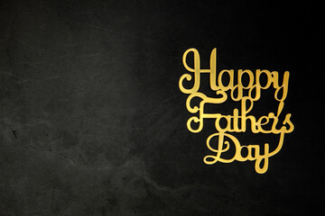 Happy Fathers Day concept. Gold shiny Letters with text Happy Father's Day on concrete dark black background Flat lay, top view, copy space
