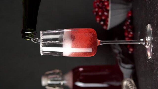 Cranberry mimosa cocktail on dark background. Cocktail garnished with sugar and fresh cranberries.