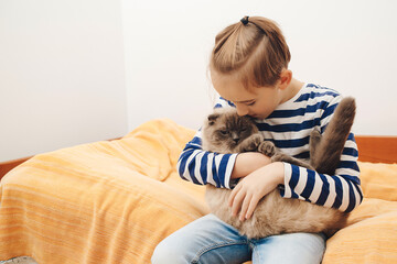 Happy kid hugging his cat. Boy relaxing on the bed with pet. Childhood, true friendship and home pet.