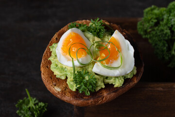 sandwich with avocado and egg, dark photo, close-up