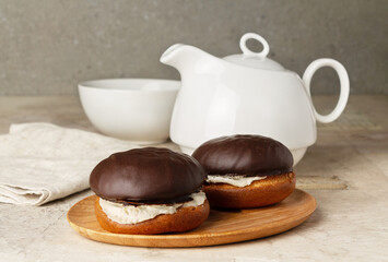 biscuit cakes in chocolate icing on the background of a teapot and a cup, on the table