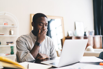 Troubled black man sitting with laptop at table