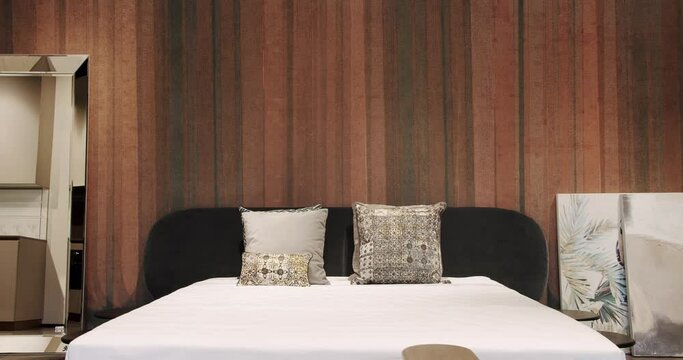 Elegant and Simple Bedroom With a King Sized Bed. Minimalist bedroom. Modern bedroom interior with furniture with double bed and pillows. Luxury home with modern brown wallpaper on the wall.