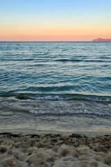 Beautiful beach of Alcudia Bay at sunset. Ocean waves at sundown. 