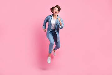 Full length photo of impressed adorable lady dressed denim jacket hurrying jumping high isolated pink color background - obrazy, fototapety, plakaty